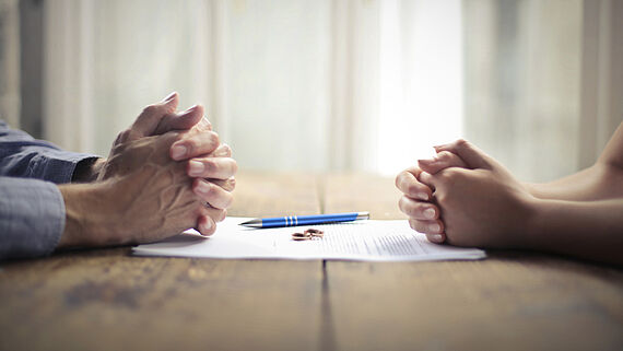 Nahaufnahme von Haenden auf den Schreibtisch: Mann und Frau haben gerade eine Scheidungsvereinbarung unterzeichnet