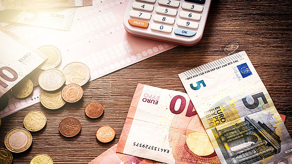auf einem Holzisch liegt Geld und ein Taschenrechner