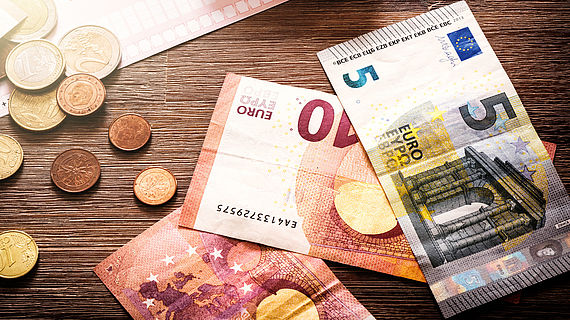 auf einem Holzisch liegt Geld und ein Taschenrechner