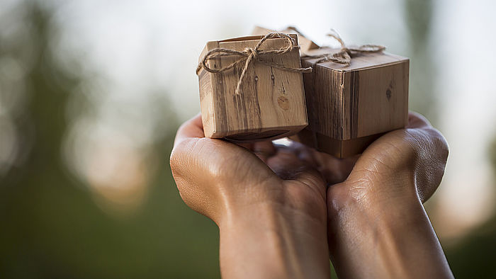 Zwei kleine Geschenkpakete werden in den Händen gehalten