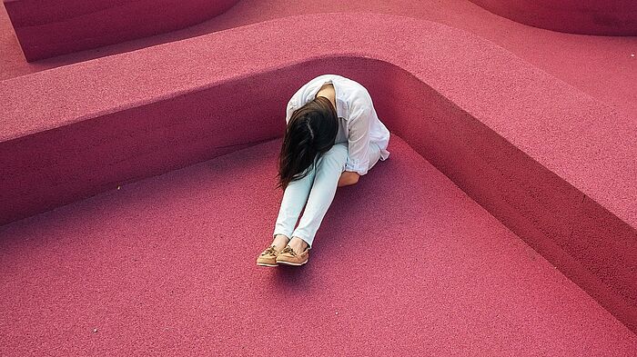 Frau in weißer Kleidung kauert auf Bodem