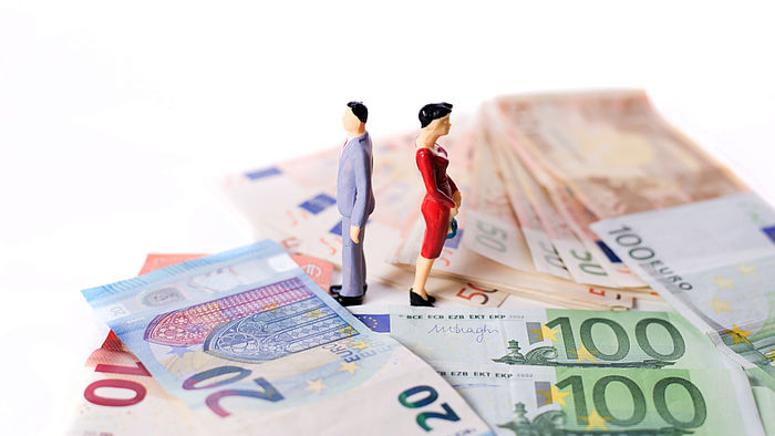 Miniaturfiguren, Mann und Frau, stehen auf Geldscheinen