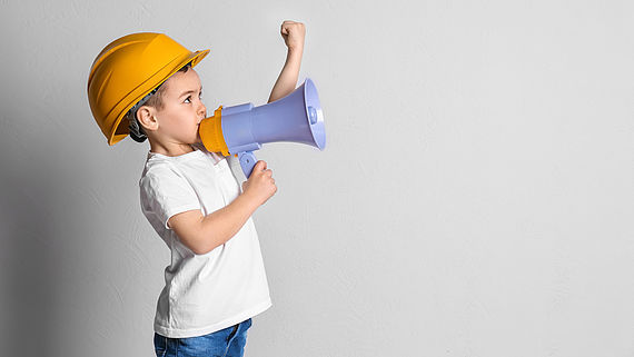 Kleiner Junge im Helm mit Megaphon
