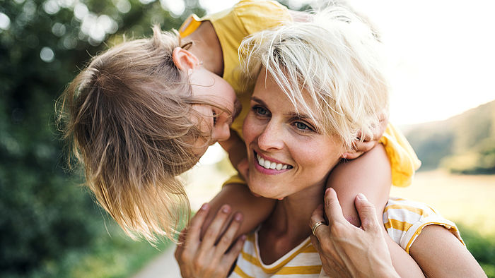 Kleines Kind sitzt bei seiner Mutter auf den Schultern