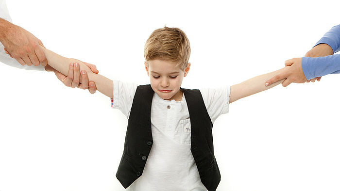 Kleiner Junge wird an jeweils einem Arm von einem Elternteil gezogen