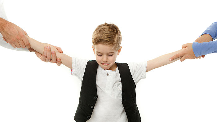 Kleiner Junge wird an jeweils einem Arm von einem Elternteil gezogen