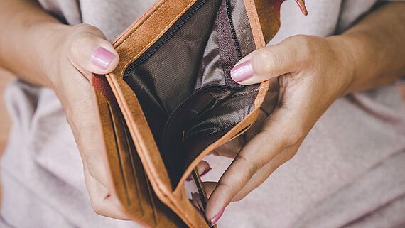 Frauenhaende halten einen leeren Geldbeutel auf
