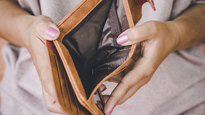 Frauenhaende halten einen leeren Geldbeutel auf