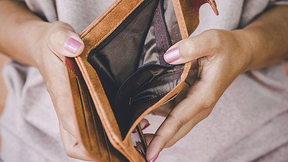 Frauenhaende halten einen leeren Geldbeutel auf