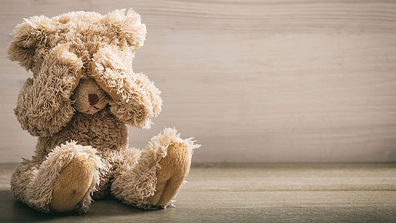 Teddybaer haelt sich mit Pfoten die Augen zu