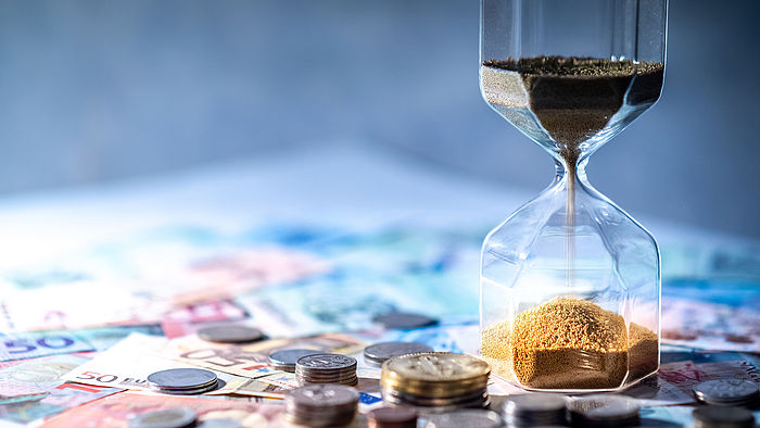 Sanduhr und Geld auf dem Tisch