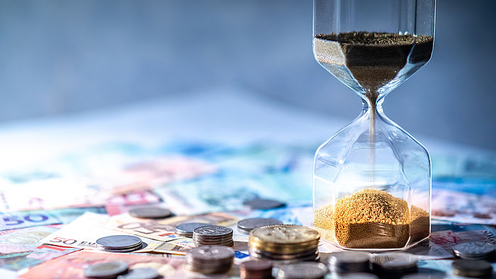 Sanduhr und Geld auf dem Tisch