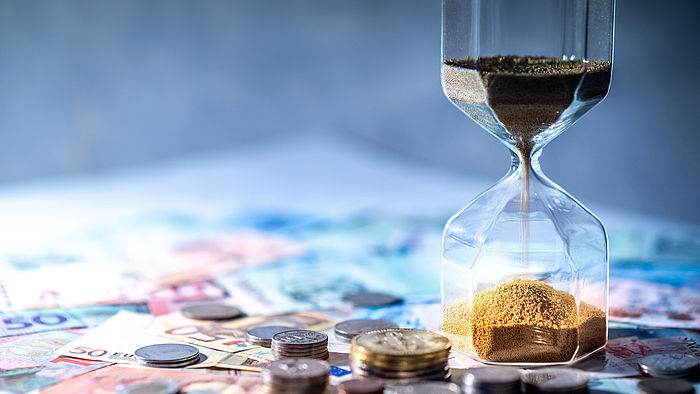 Sanduhr und Geld auf dem Tisch