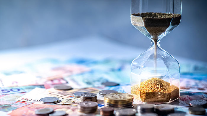 Sanduhr und Geld auf dem Tisch
