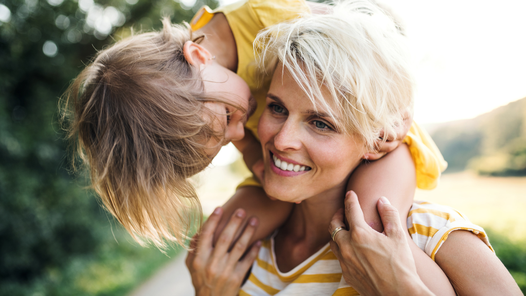 Mutter in der Natur mit der kleinen Tochter auf den Schultern