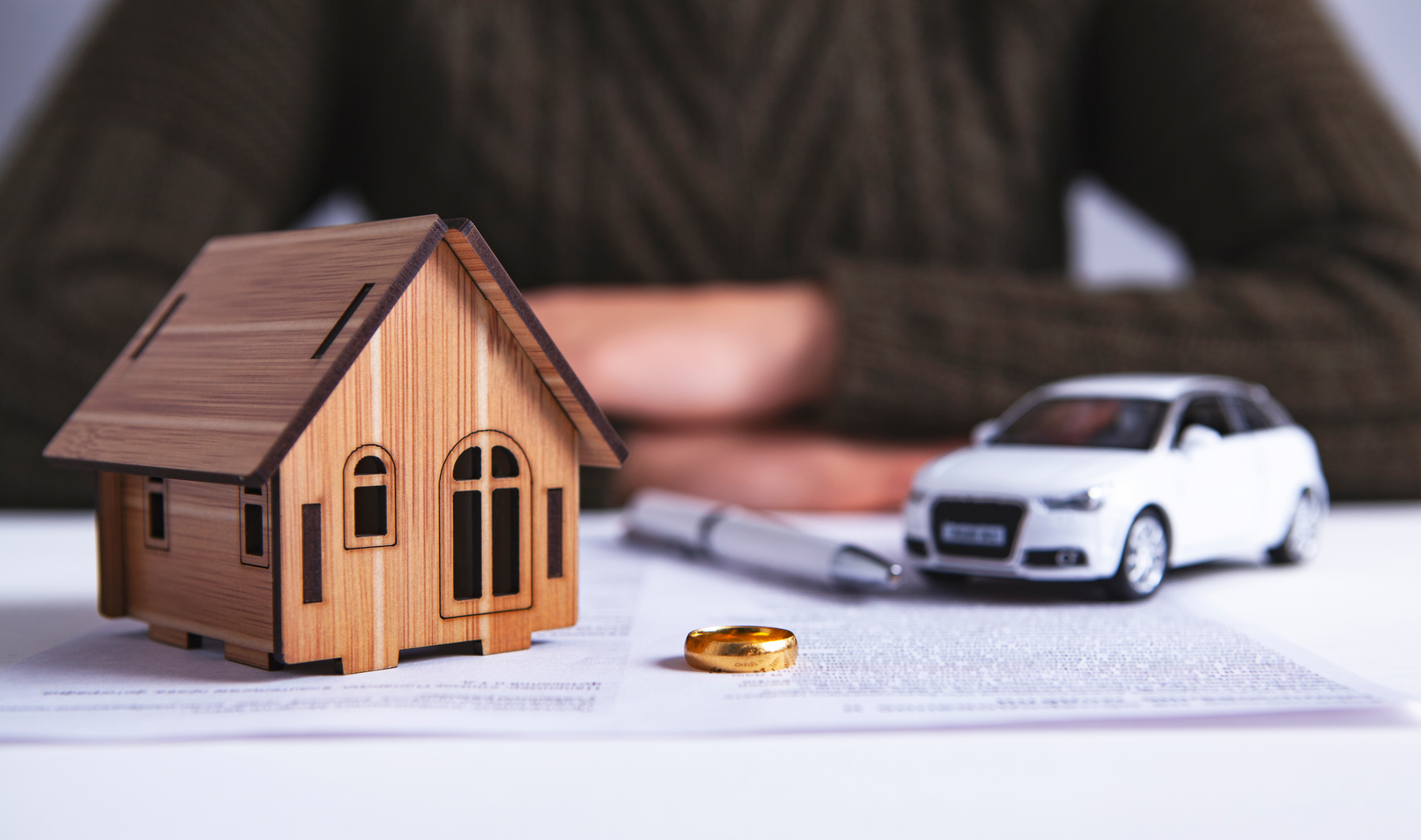 Vereinbarung mit Stift, ein Spielzeugauto, ein Ring und ein Miniholzhaus