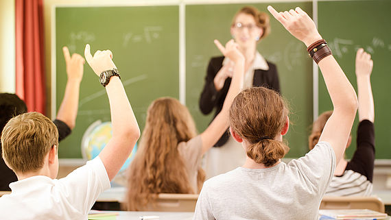 Schueler melden sich in der Klasse