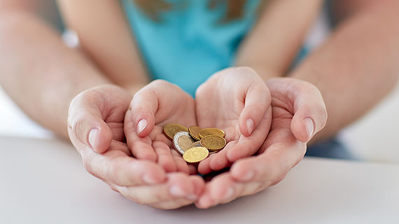 Nahaufnahme von Familienhaenden, die Euro-Geldmuenzen halten