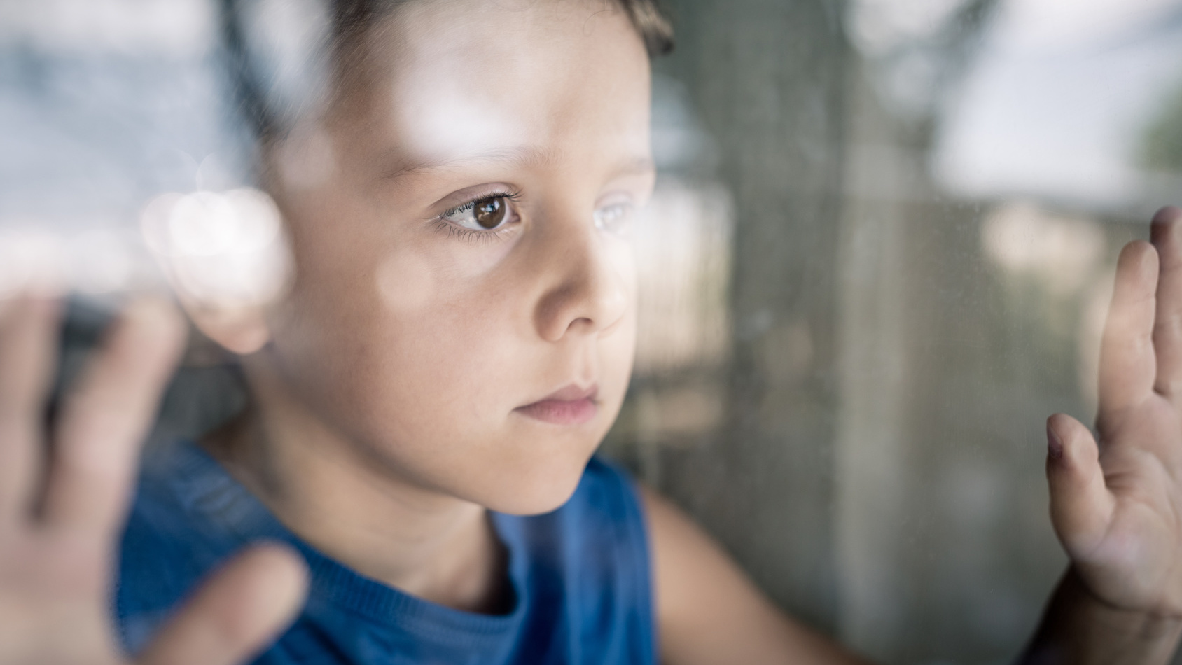 Junge schaut traurig aus dem Fenster