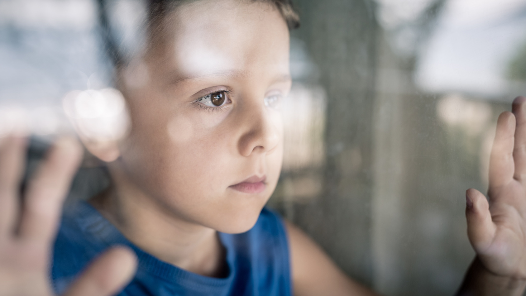Junge schaut traurig aus dem Fenster