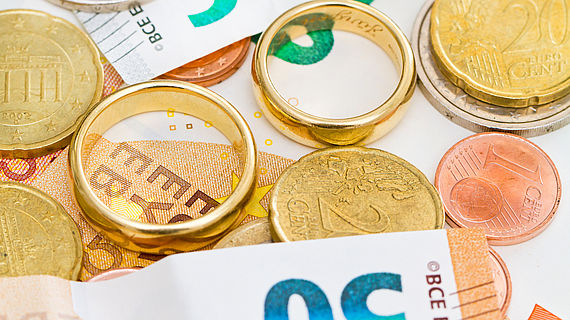 Eheringe liegen zwischen Euro-Banknoten und Muenzen