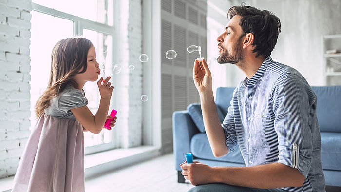 Vater pustet mit seiner kleinen Tochter Seifenblasen