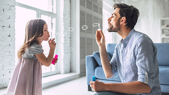Vater pustet mit seiner kleinen Tochter Seifenblasen
