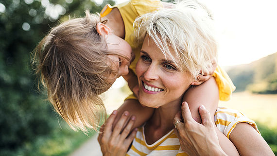 Kleines Kind sitzt bei seiner Mutter auf den Schultern