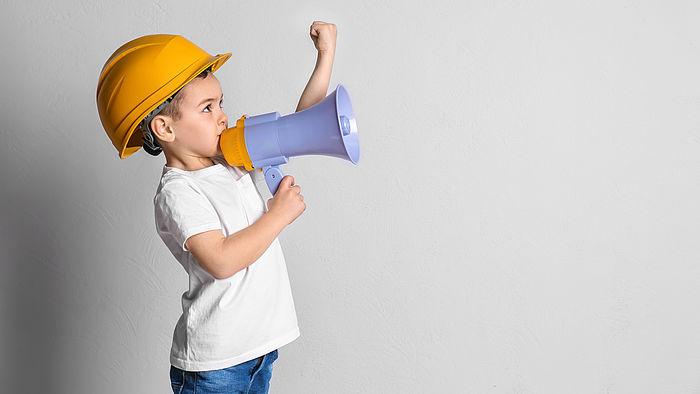 Kleiner Junge im Helm mit Megaphon