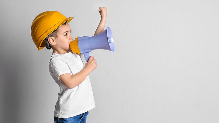Kleiner Junge im Helm mit Megaphon